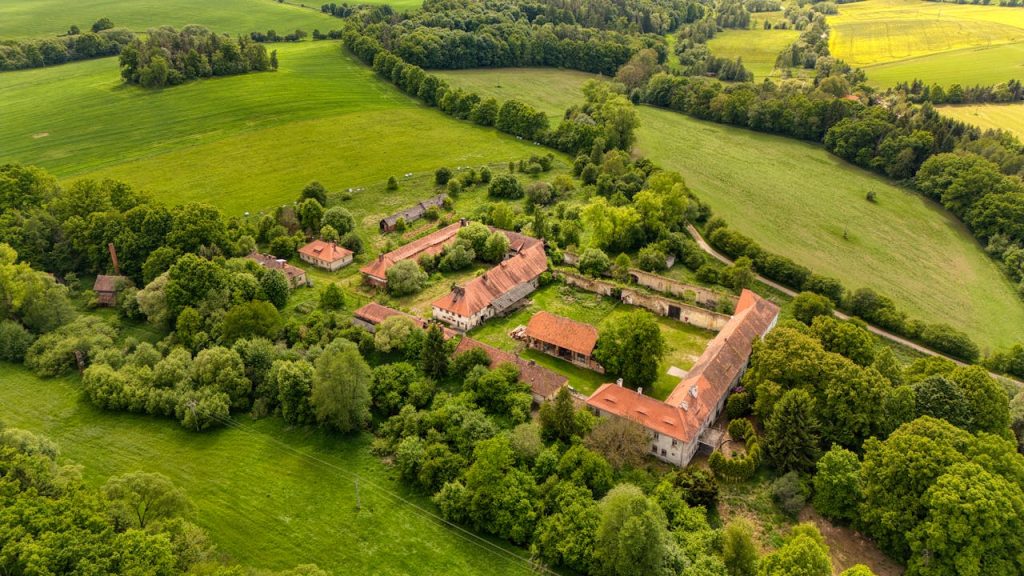 Aerial drone capture of a scenic rural village in the lush Czech countryside surrounded by vibrant green fields.