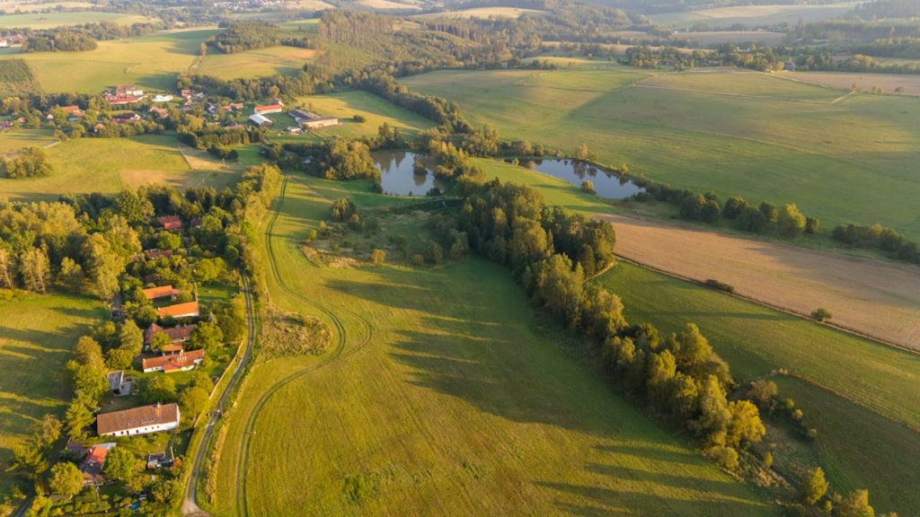 Aerial view of the lush green countryside in Zbraslavice, highlighting fields and ponds at sunset.